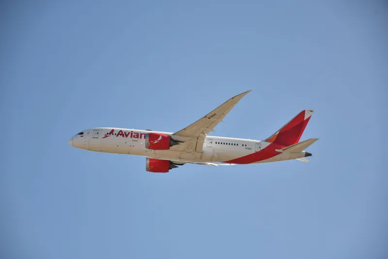 An Avianca Boeing 787 climbing away after takeoff against a clear blue sky