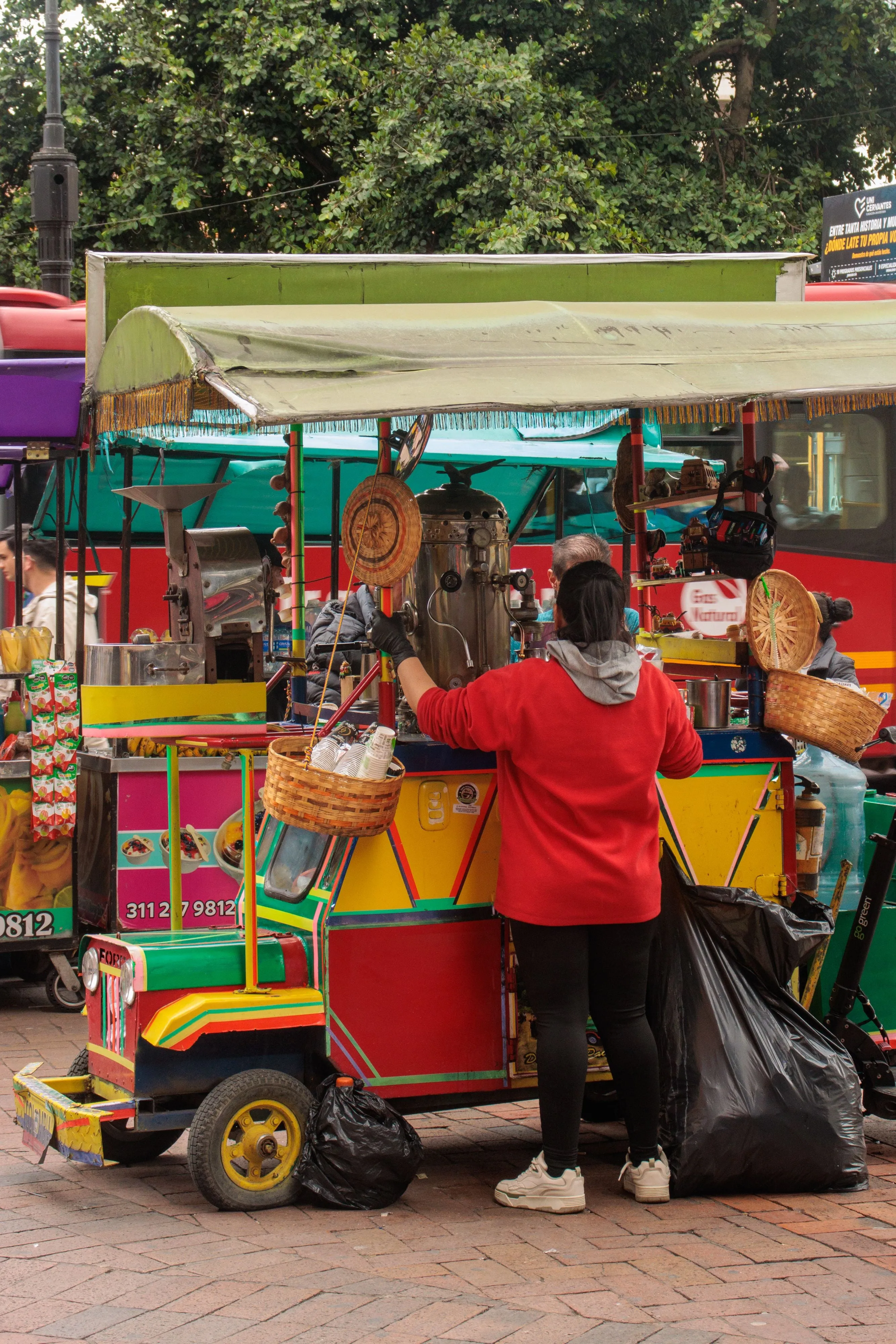 A brightly painted street cart selling juices and coffee, with a vendor working behind it
