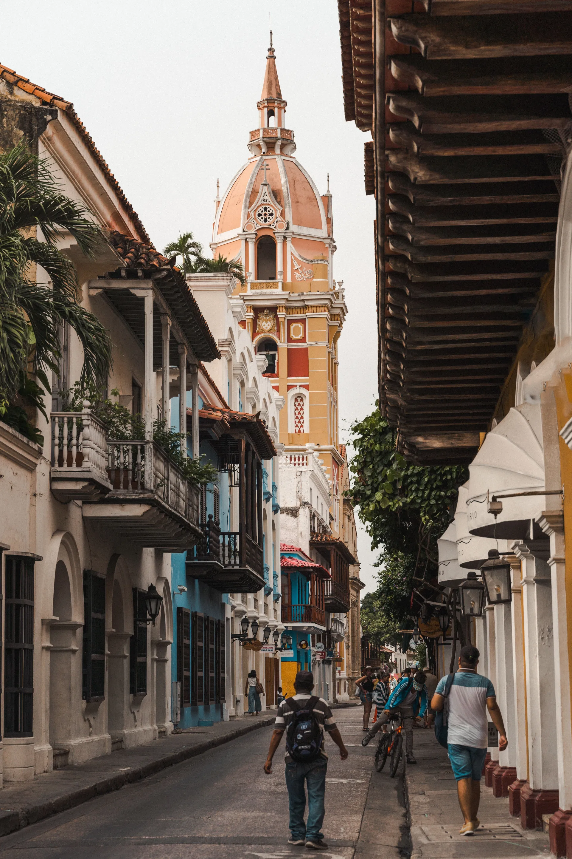 A street of wooden balconies in Cartagena's walled city, leading to the domed bell tower of the cathedral