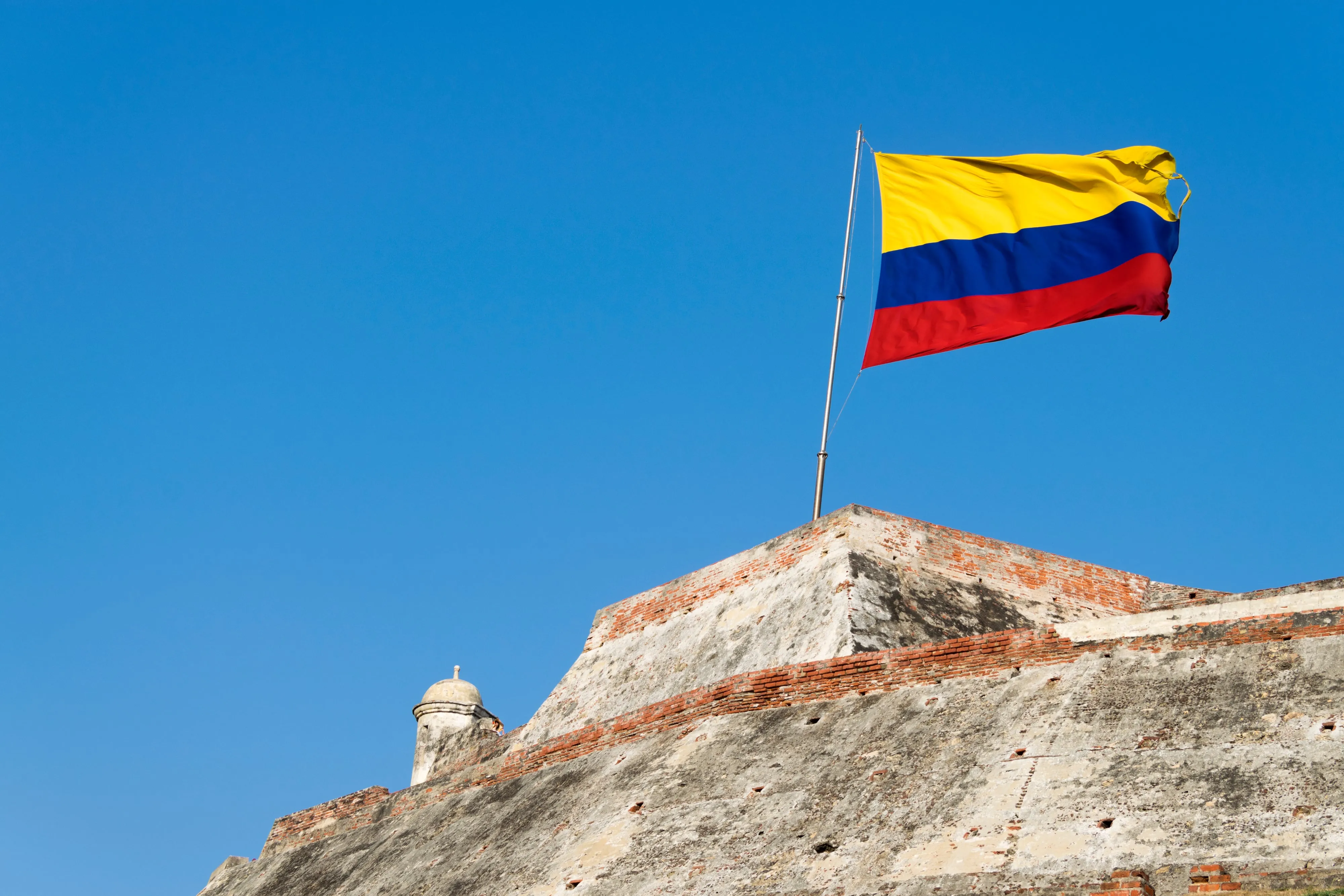 The Colombian flag flying over the ramparts of Castillo San Felipe de Barajas with the fortress stonework behind