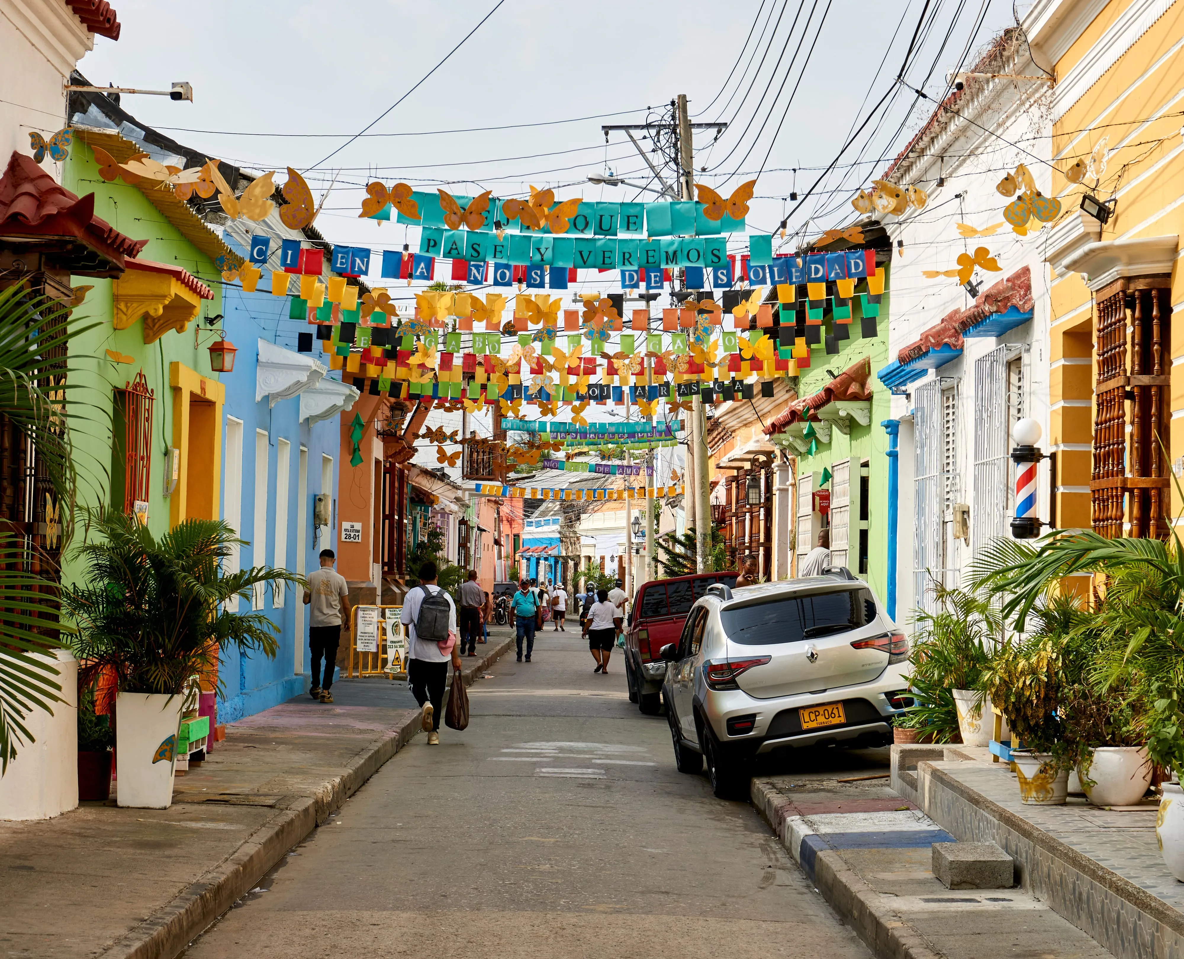 A colorful street in Cartagena's Getsemaní neighborhood, strung with bunting, with people walking past painted houses