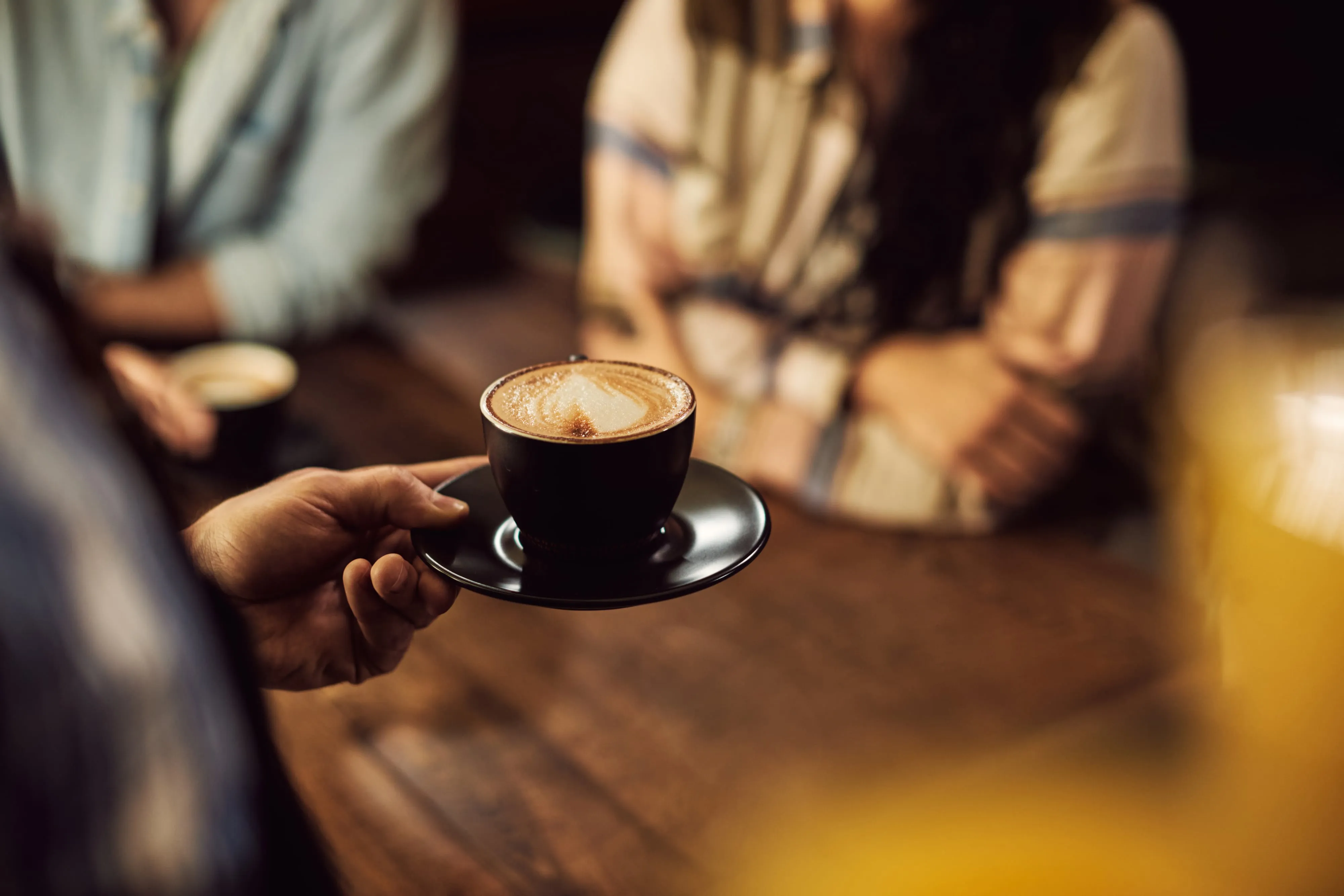 A barista serving a freshly poured cappuccino in a café