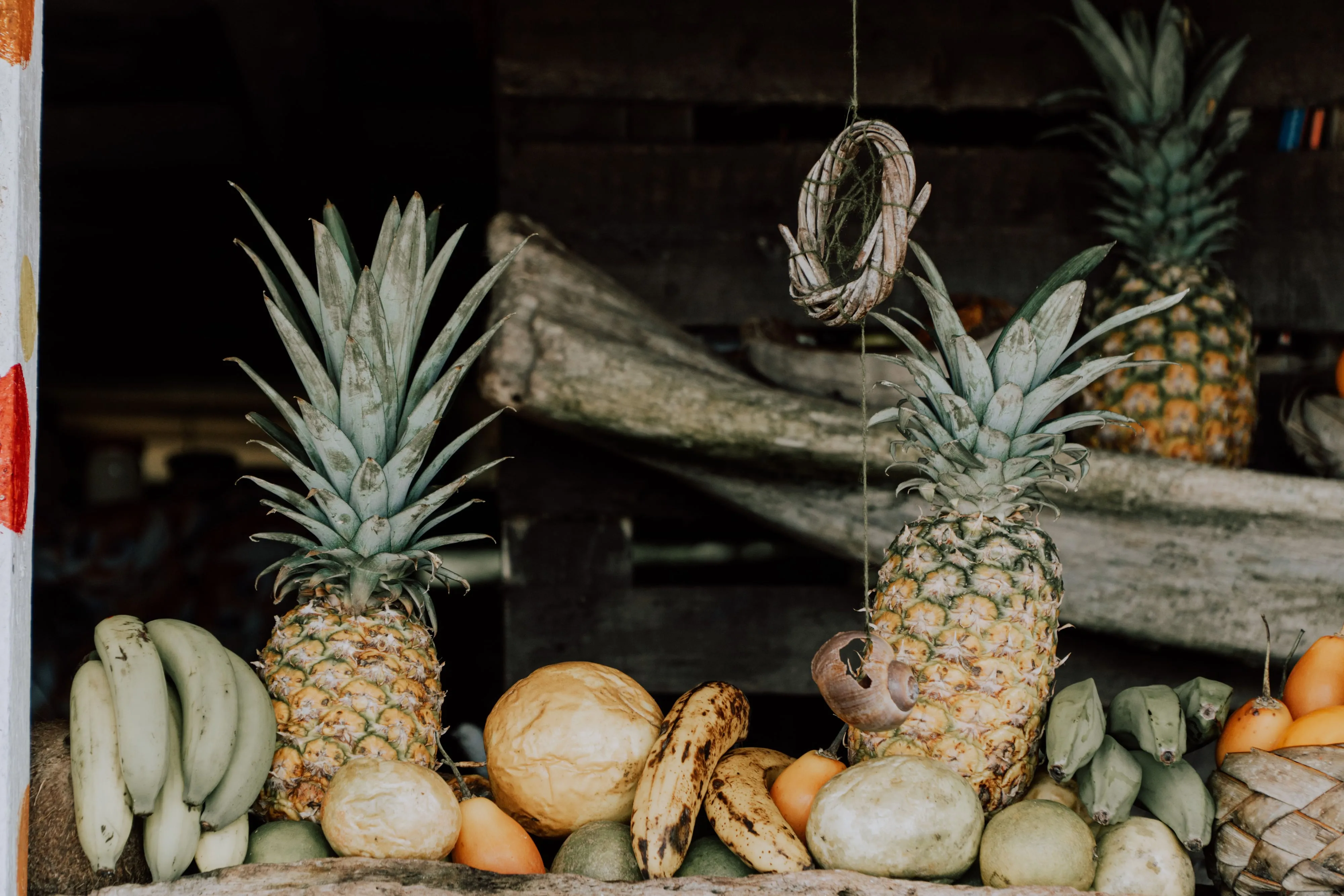 Pineapples and bananas piled at a tropical fruit stall in a Colombian market