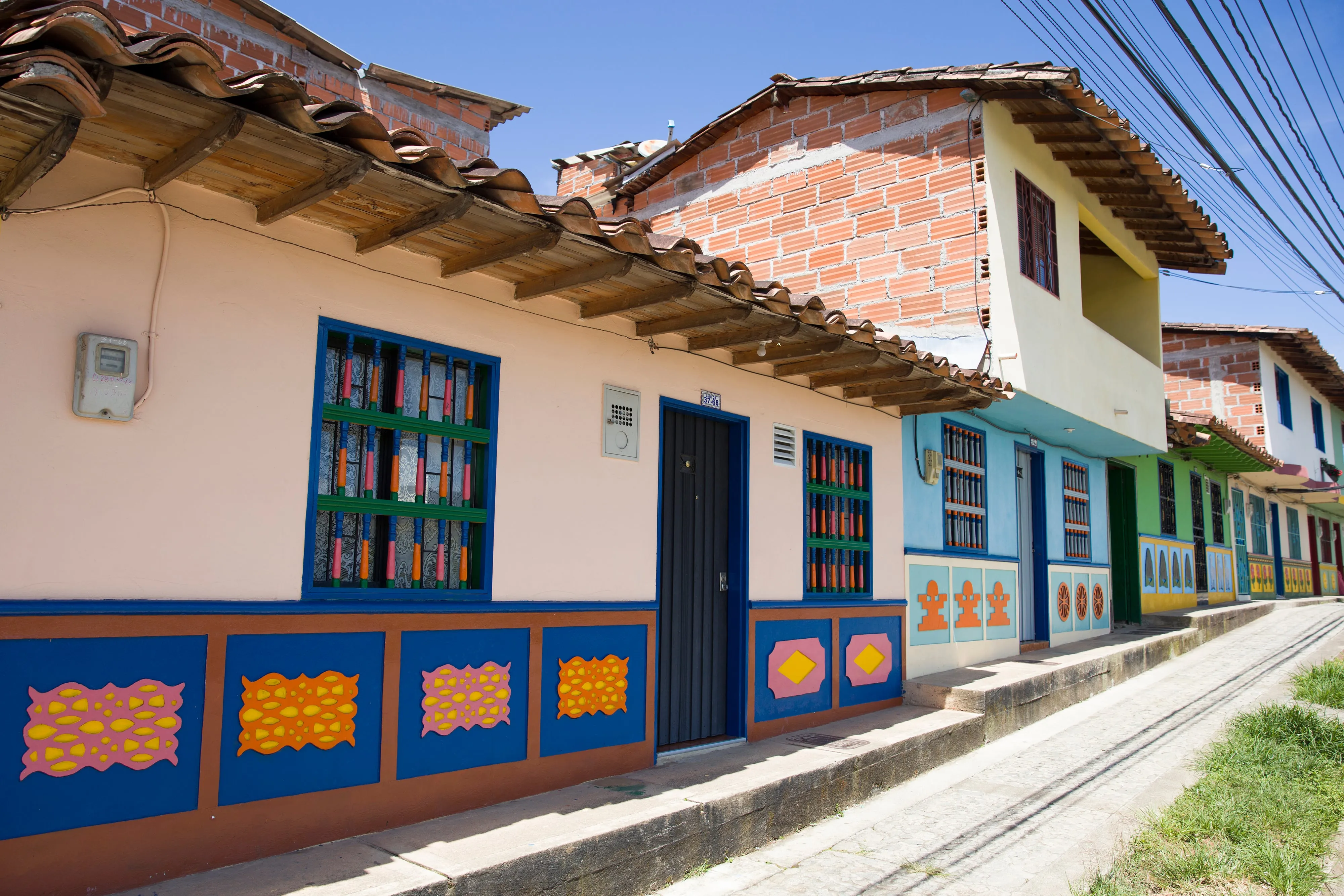 A narrow Guatapé street lined with buildings painted in bright colors, each with sculpted relief panels along the base