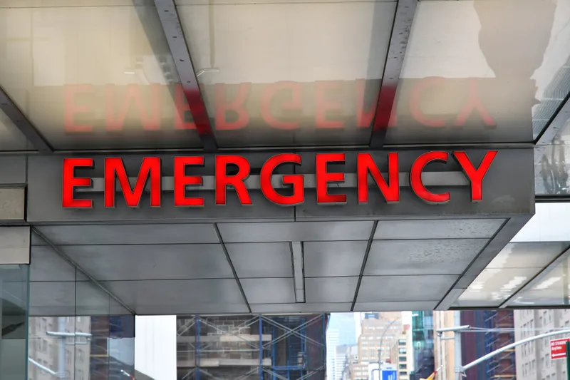 A red illuminated EMERGENCY sign above the entrance to a hospital