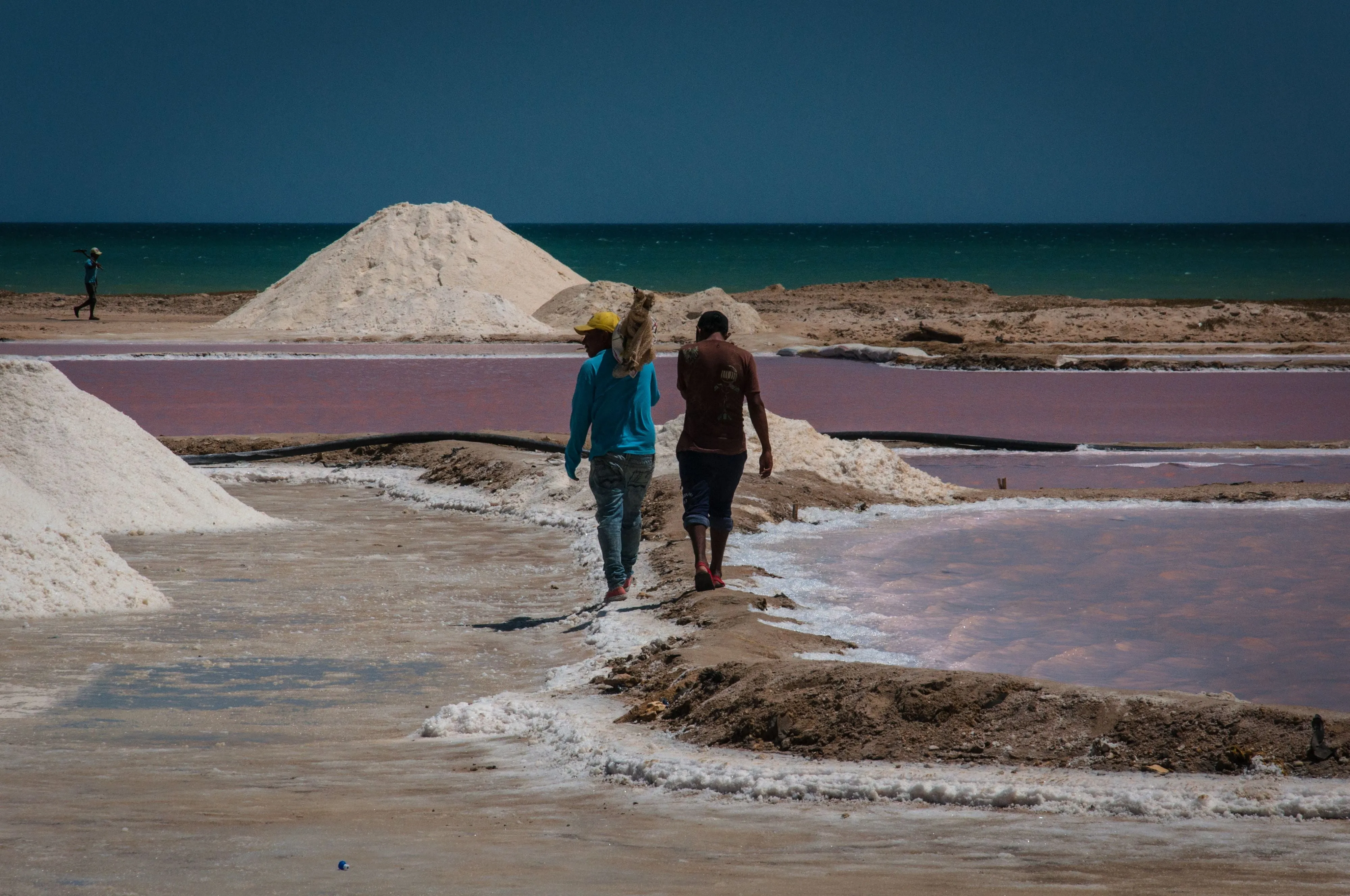 Workers walking past pink salt pans near Manaure in La Guajira, Colombia