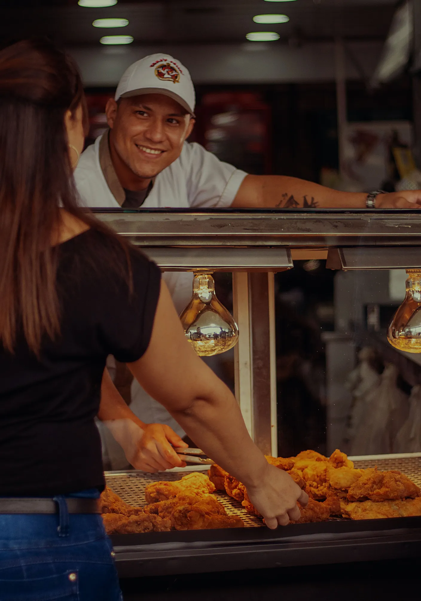 A street food vendor at a lit counter handing over fried snacks to a customer