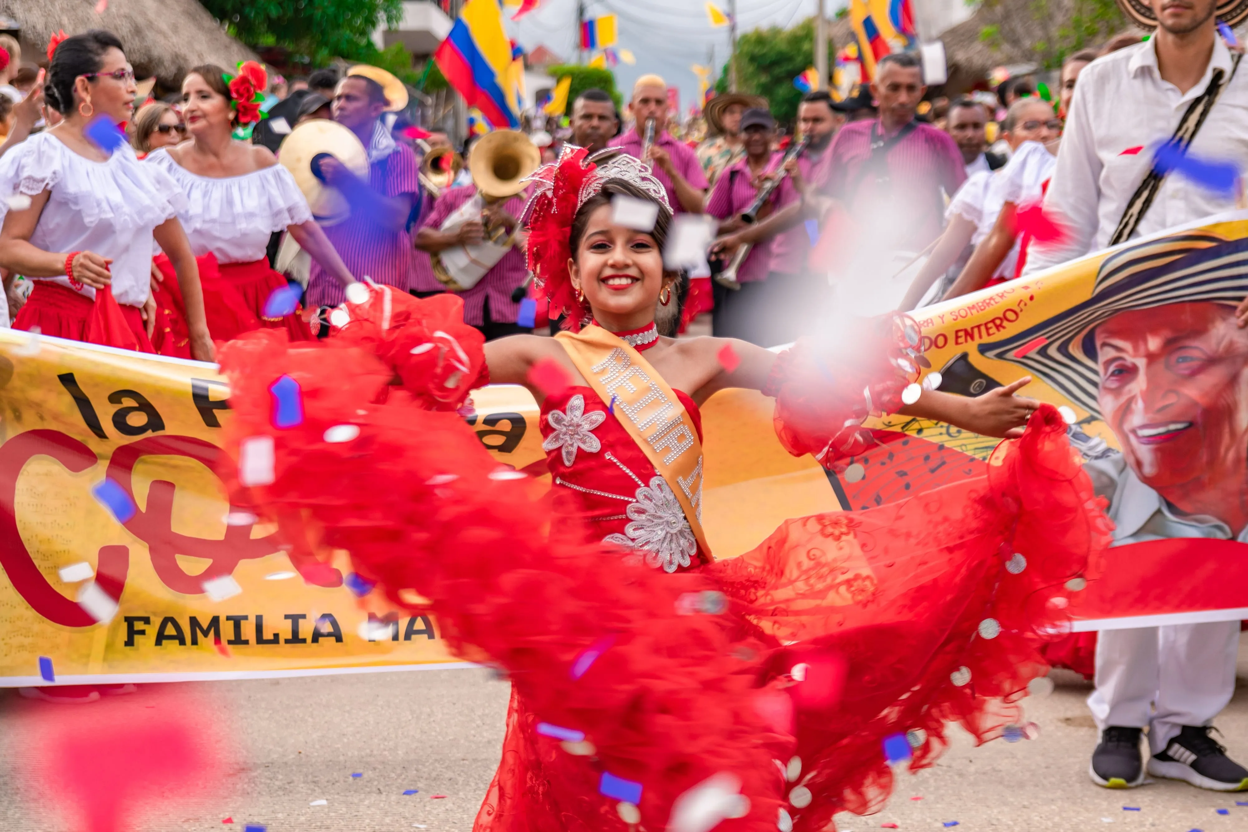 A brass band in matching shirts playing behind a costumed dancer during a small-town street parade