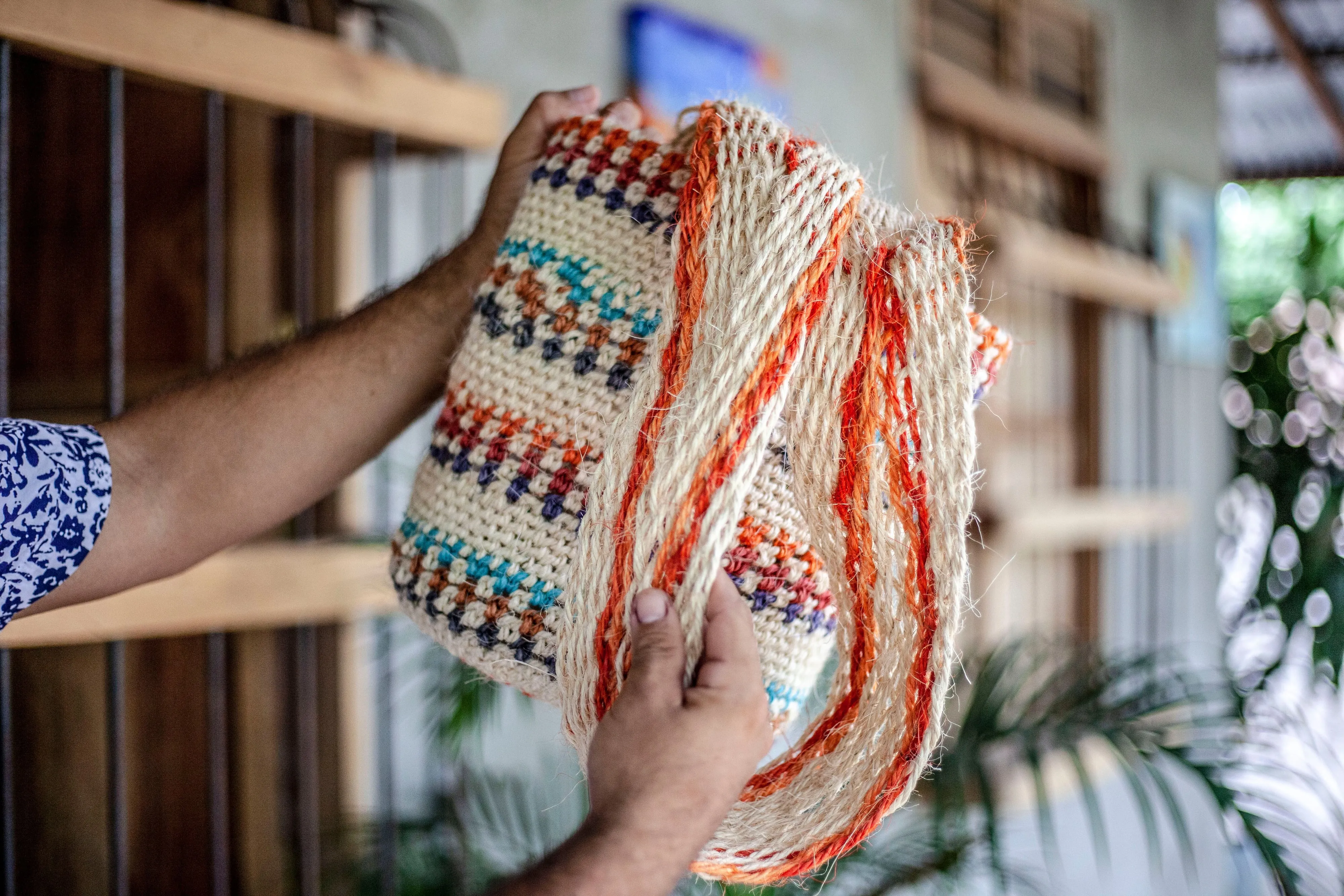 Hands holding a colorfully woven Wayuu mochila bag